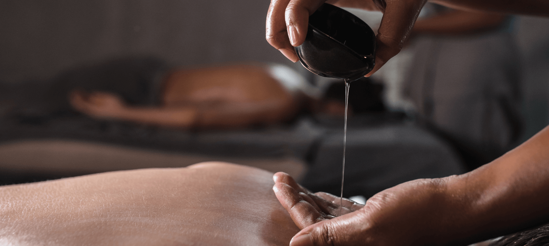 Person pouring oil on their hand to give a massage