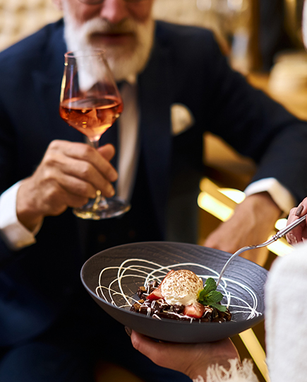 person holding a plate with food and man holding a glass of wine 