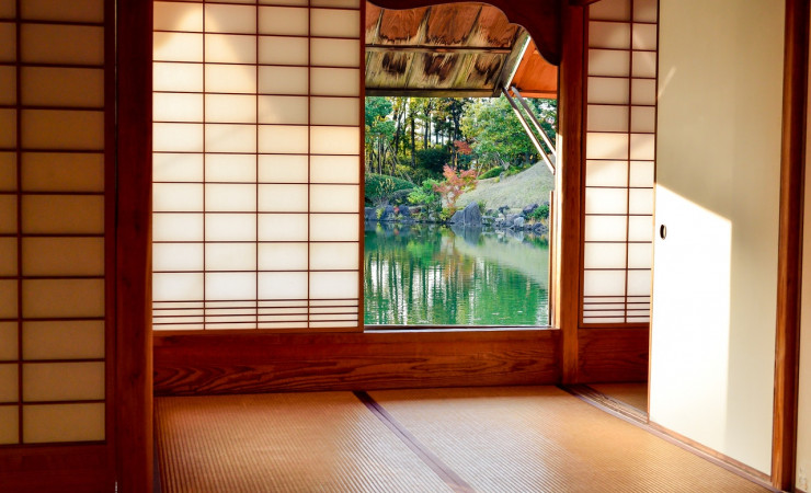 Interior of Japanese home with paper walls and door opening onto pond and garden