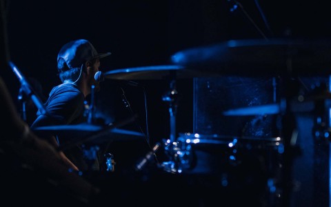 View of a young man wearing a cap playing drums 