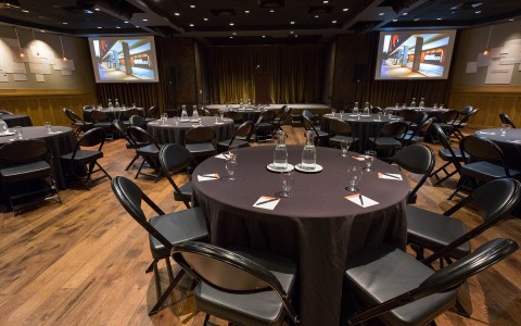 Meeting room set up with round tables and a screen