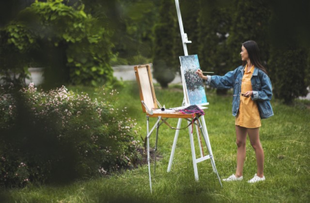 woman in yellow dress and denim jacket painting