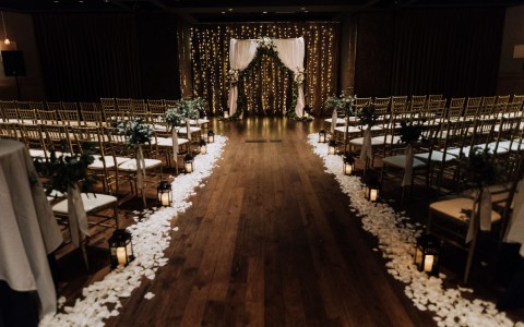 indoor wedding ceremony with flower petals lining the aisle up to the alter