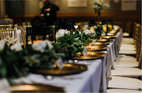 long banquet table with gold and green place settings and centerpieces