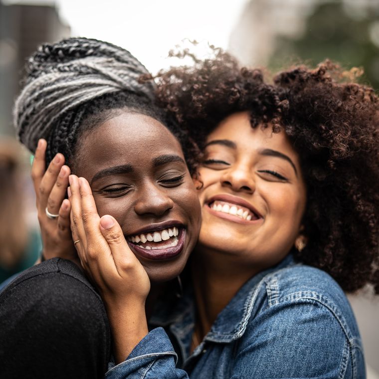 two black women embracing each other face to face smiling