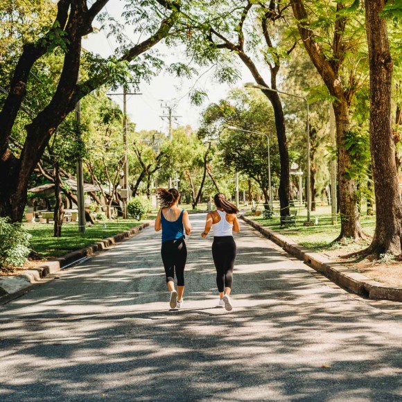 two people jogging outside under trees