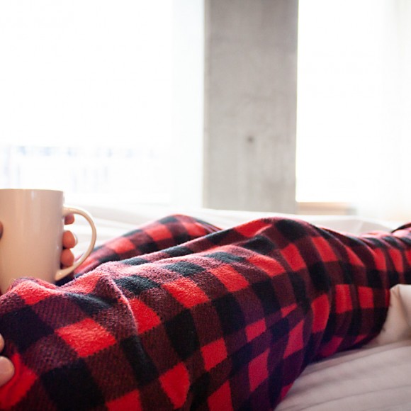 person's crossed legs on top of bed wearing cozy red and black flannel pants