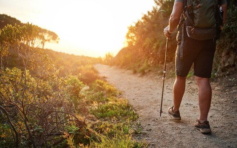 man hiking along a dirt path during sunset 