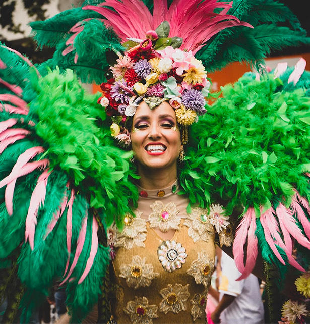 young woman dressed for carnival wearing green feathers and a floral headdress