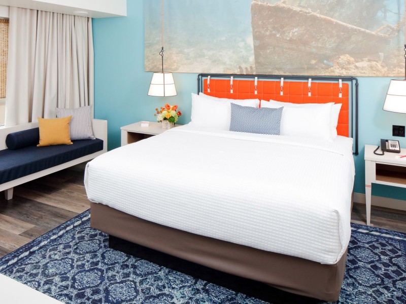 a king bed with orange headboard and white linens