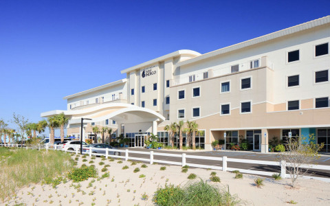 front of hotel behind sandy dune on a clear sunny day