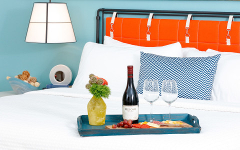 wine and cheese serving tray on white bed linen