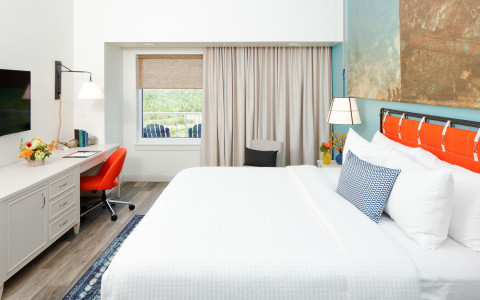 guest room with king bed and desk area with orange chair
