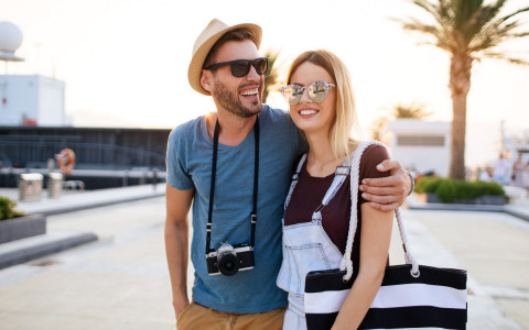 tourist couple walking together in sunglasses with camera