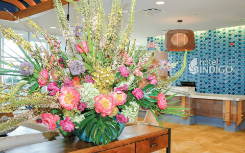 large floral arrangement in hotel lobby with front desk in background