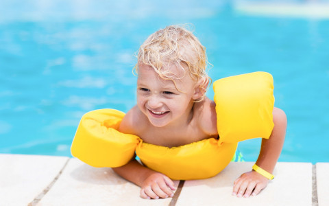 smiling child climbing out of pool with bright yellow float