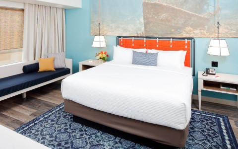 guest room with queen bed in light blue guest room and seating bench