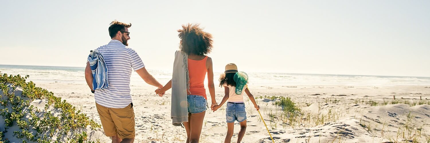 a family holding hands and walking on the beach