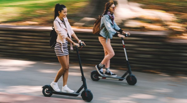 two girls riding scooters