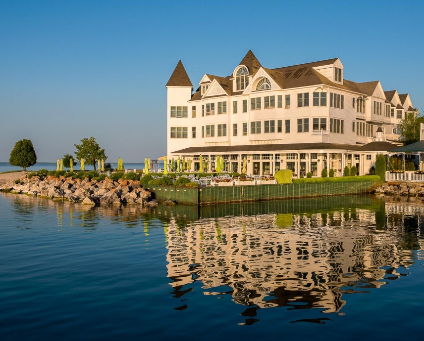 view of white hotel building and patio from the water