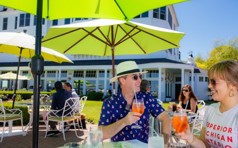 man with drink in hand under green umbrellas