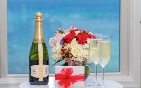 bottle of champagne next to vase of flowers and glasses of champagne