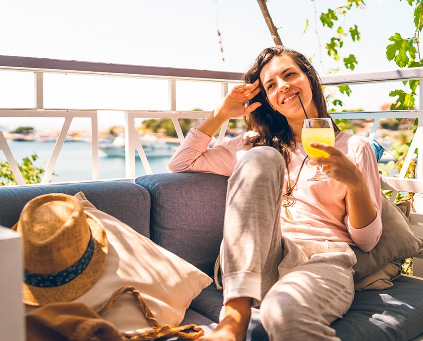 woman sitting on balcony while holding yellow drink