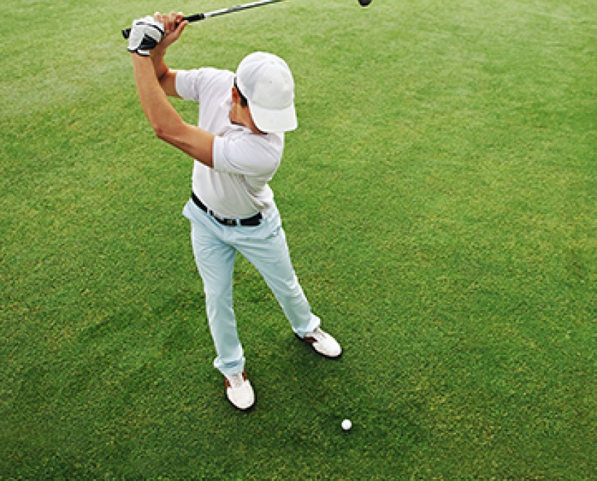 overhead view of a man swinging back a golf club while wearing white