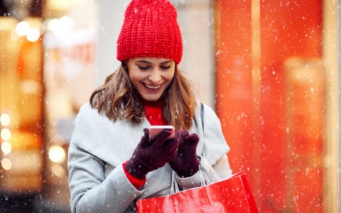 Lady on her phone with shopping bag in snow