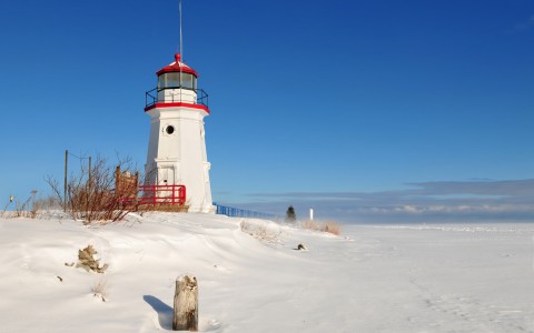 lighthouse on the beach withs now during the day