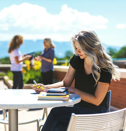 woman sitting at outdoor table with books and notepad