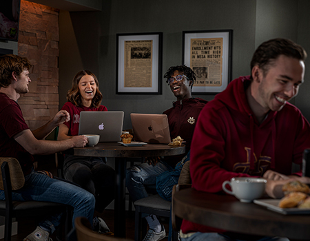students in a coffee shop doing homework and talking