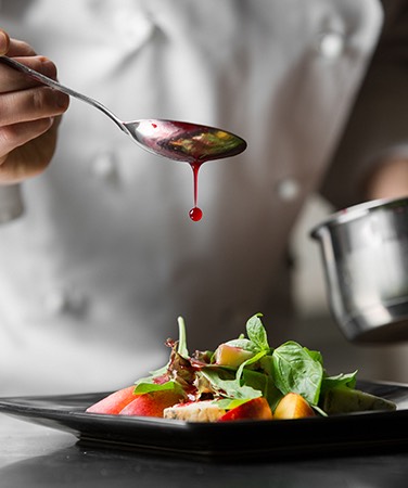 chef drizzling pink sauce on food