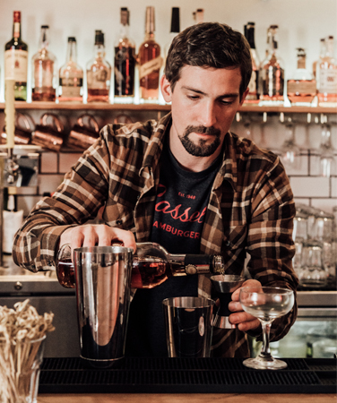 a bartender making a cocktail behind a bar