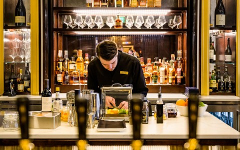 bartender slicing fruit in front of the bar at the counter