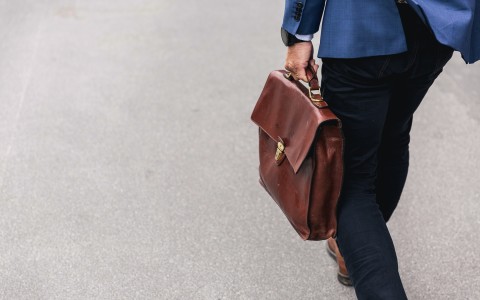 man in suit carrying a brown briefcase 