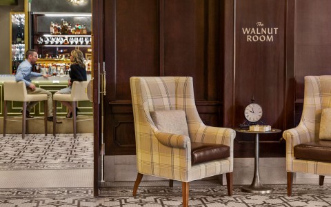 two armchairs in front of the walnut room with the bar in the background 