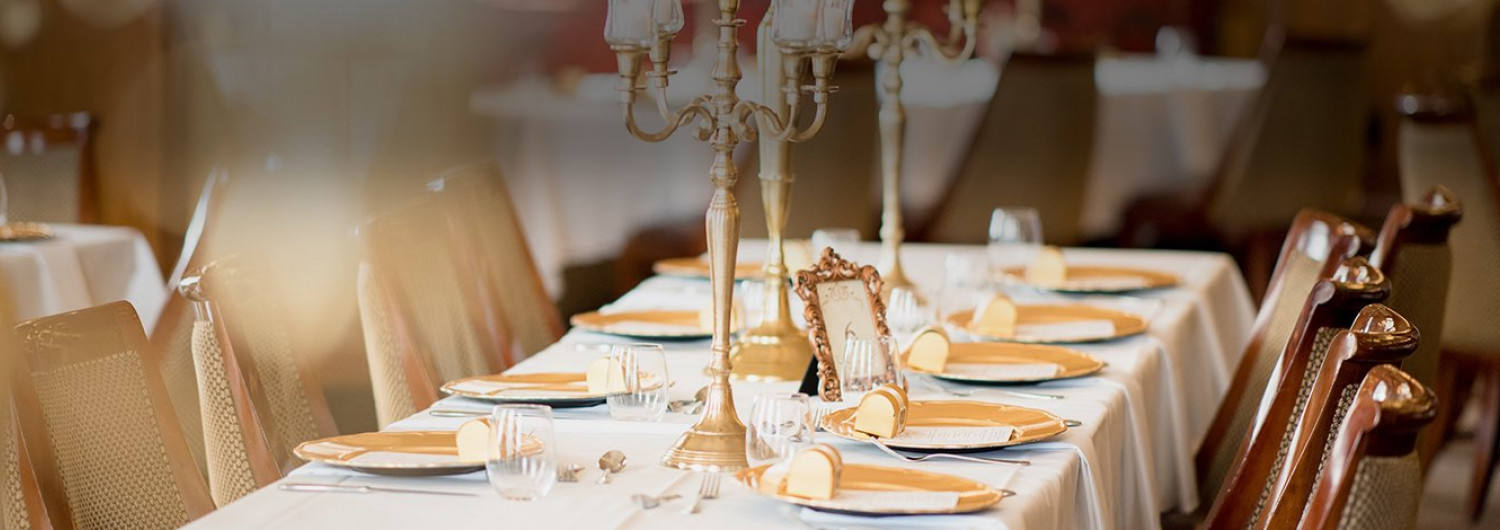 wedding reception table with white table cloths, gold accents, and candle stick centerpieces