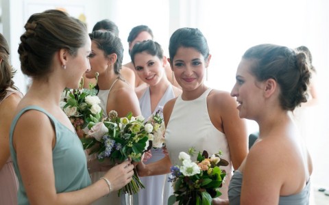 bride smiling and holding the bouquet around her bridesmaids 