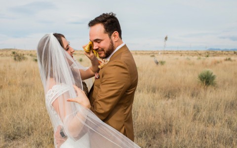 a bride cleaning the grooms tears in a field 