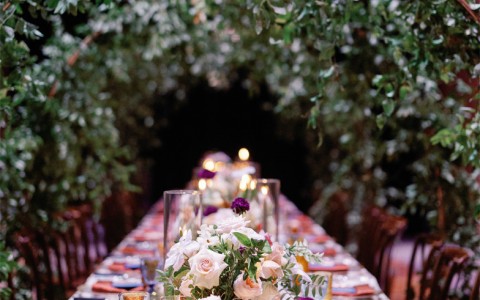 a wedding reception tables set up with glasses and green arcs 