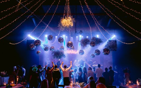 wedding celebration with people dancing, decorated with mirrorballs and lights