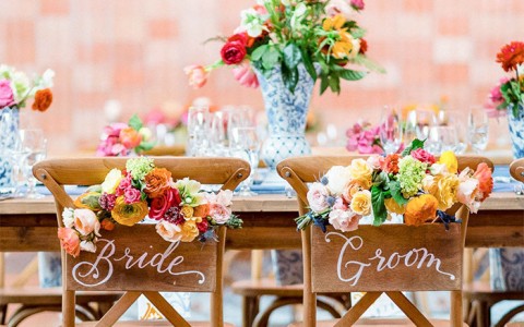 a reception table set up with chairs decorated saying bride and groom and flowers on vases and on the chair