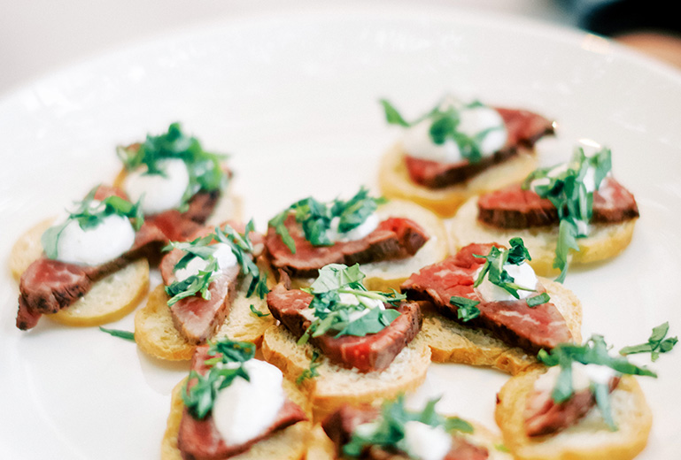 little bread with a piece of meat on top garnished with cilantro