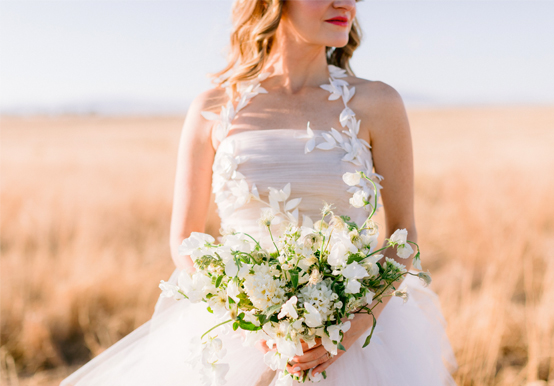 bride holding a bouquet with a wheat field as the background