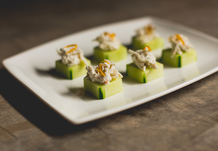 close up view to a plate with small pieces of cucumber with chicken on top