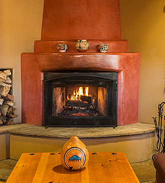 Fireplace with fire and coffee table with native american art on it