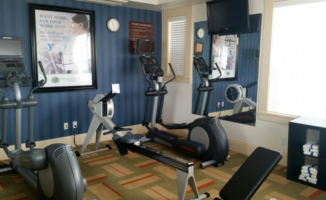 Fitness room with elliptical, row machine, another elliptical and a mirror