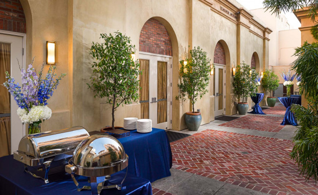 Outdoor courtyard set up with catering and decorated with potted trees