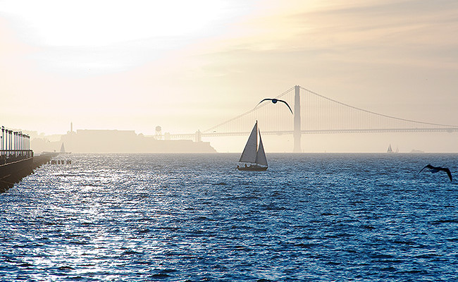 sailboat in the water at dusk with the golden gate bridge in distance